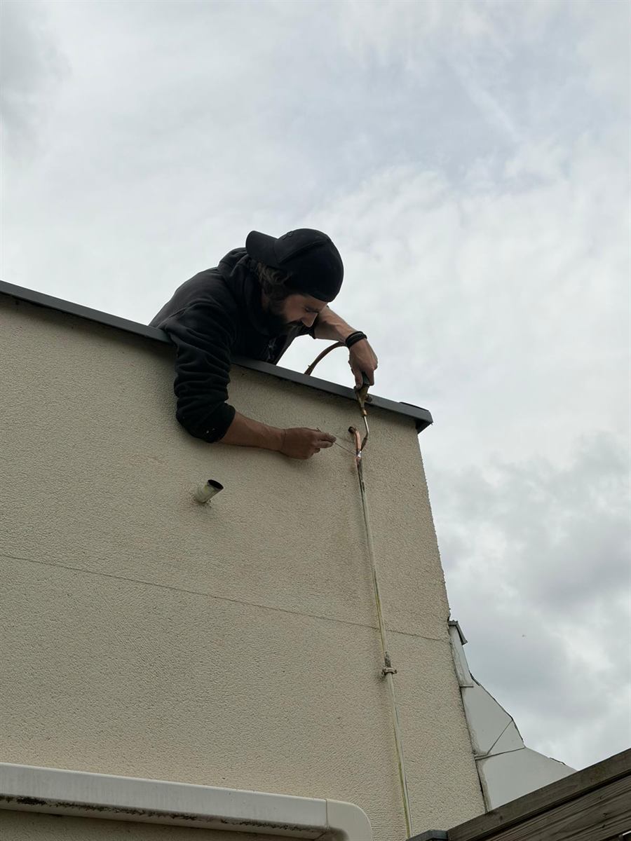 Soudure d'un tuyau en cuivre neuf en façade d'un pavillon